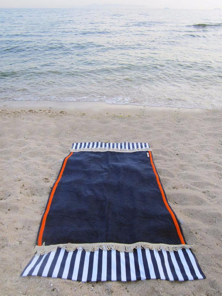 Beach towel in navy blue color with two extra panels of striped cotton fabric on its sides and cotton fringes