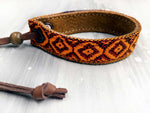 Leather bracelet with an orange woven ribbon and Aztec pattern