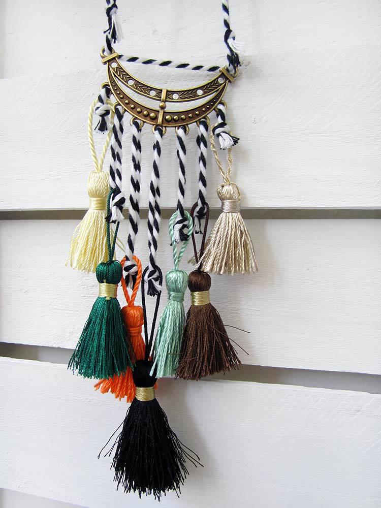 Pendant with an adjustable height cord and several rayon tassels with a bronze metal moon-shaped trim